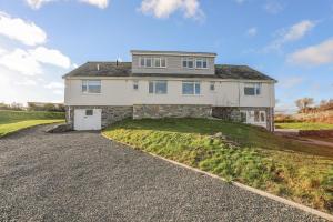 a large white house on a hill with a driveway at Braid Apartment in Trearddur