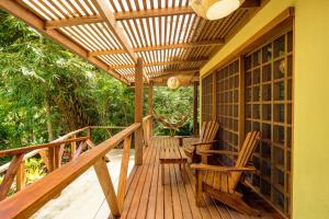 a wooden deck with two chairs and a pergola at Las Palomas Villas in Cocles