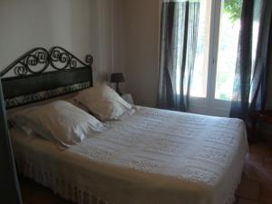 a bedroom with a bed with white sheets and a window at Michèle et Didier Lin in Saint-Laurent-dʼAigouze