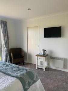 a bedroom with a bed and a tv and a chair at Kinloch Lake & Golf Views in Kinloch