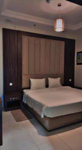 una camera con un grande letto con testiera in legno di الشاطئ الأبيض للشقق المخدومة a Rayyis