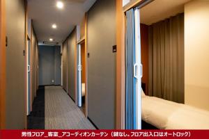 um corredor de um quarto de hotel com uma cama em R9 Hostel Tochigi Ekimae em Tochigi