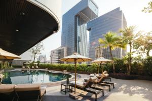 a pool with chairs and umbrellas in a city at Grand Fortune Hotel Bangkok - SHA Extra Plus in Bangkok