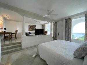 a bedroom with a bed and a table and a window at VILLA JADE LUXURY FULL SERVICE STAFF VILLA in Acapulco