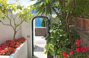 an open doorway to a garden with red flowers at Villa Mariuccia Capri in Capri