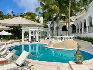 a swimming pool in a house with chairs and an umbrella at VILLA JADE LUXURY FULL SERVICE STAFF VILLA in Acapulco