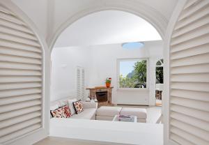 a living room with white furniture and an archway at Villa Mariuccia Capri in Capri