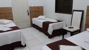 una habitación de hotel con 2 camas y una silla en Hotel Vila Real, en Araçatuba
