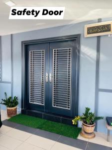 a blue door on a building with two potted plants at No 11 Nazirin Homestay Tmn Desa Manjung Lumut in Lumut