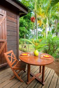 une table en bois et une chaise sur une terrasse dans l'établissement Baobab et Palmiers, à L'Étang-Salé