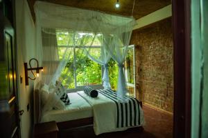 a bedroom with a white bed with a window at Ella Rock Grun Cottage in Ella