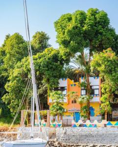a boat in front of a building with trees at Awi Guest House in Aswan