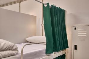 een slaapkamer met een groen gordijn naast een bed bij Hola Hostal Collblanc in Hospitalet de Llobregat