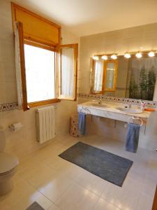 ein Badezimmer mit einem Waschbecken, einem WC und einem Spiegel in der Unterkunft Villa San Lure Jaca in Jaca