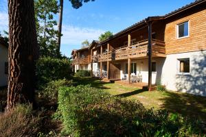 - une vue sur l'extérieur d'une maison avec un arbre dans l'établissement Les Cottages Du Lac, à Parentis-en-Born