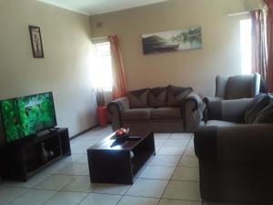 a living room with a couch and a tv at Vuya Nathi Bed and Breakfast in Manzini