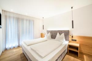 1 dormitorio con 1 cama blanca grande con almohadas blancas en Oberegghof Ferienwohnung Garten, en Rifiano