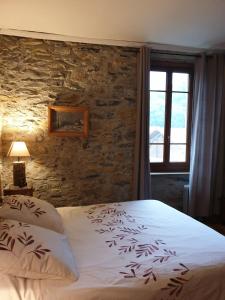 1 dormitorio con cama y pared de piedra en chambre et table d'hôtes La Grande Ourse, en Sauveterre