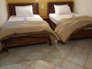 dos camas sentadas una al lado de la otra en una habitación en Tropic Garden Hotel, en Banjul
