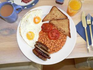 a plate of breakfast food with eggs sausage beans and toast at Hotel Westend Holiday Home 5 mint from Nizamuddin Railway Station in New Delhi