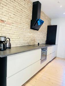 a kitchen with white cabinets and a brick wall at aday - Central cozy and bright apartment in Aalborg