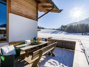 a wooden deck with a table and chairs in the snow at Haus am Feld in Kitzbühel