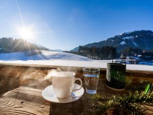 a cup of coffee and a glass of water on a table at Haus am Feld in Kitzbühel