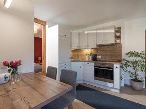 a kitchen with white cabinets and a wooden table at Haus am Feld in Kitzbühel