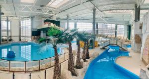 a large indoor swimming pool with palm trees in a building at Apartament Marbud przy Aquaparku Reda in Rumia