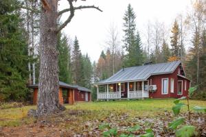 a red house in the woods with a tree at Haapaniemi Cottages in Iisalmi
