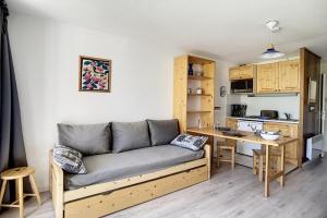 a living room with a couch and a kitchen at travelski home classic - Résidence Caron in Les Menuires