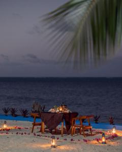 een tafel op het strand met kaarsen en verlichting bij Moja Tuu The Luxury villas & Nature Retreat in Kiwengwa