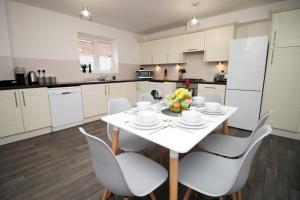 uma cozinha branca com uma mesa e cadeiras brancas em DELFT - Spacious Home, High Speed Wi-Fi, Free Parking, Terrace em Swindon