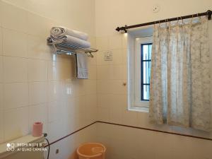 a bathroom with a toilet and a window and towels at Happy Homestay in Jaipur