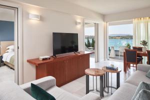 AKS Porto Heli Hotel في بورتوخيلي: غرفة معيشة مع تلفزيون وأريكة وطاولة