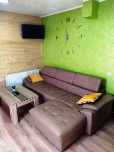a living room with a couch and a clock on the wall at Apartman Golub Sevojno in Užice +17 photos