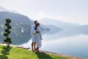 um homem e uma mulher ao lado de um lago em SEEGLÜCK Hotel Forelle Superior em Millstatt