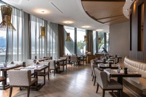 ein Restaurant mit Tischen und Stühlen und großen Fenstern in der Unterkunft AlpenGold Hotel Davos in Davos