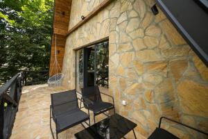 a patio with two chairs and a stone wall at Kežman Mountain Houses in Kopaonik