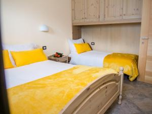 dwa łóżka w pokoju z żółto-białym w obiekcie Residence Pedranzini w mieście Bormio