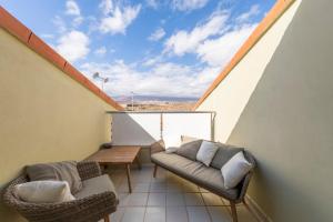 - un balcon avec un canapé et une table sur le toit dans l'établissement MEDANO4YOU Barefoot Beach House, à El Médano