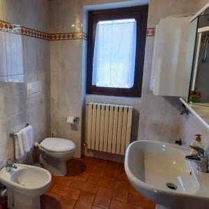 a bathroom with a white toilet and a sink at Cascina Ca' Scarlatta - Your Mountain Holiday in Introbio