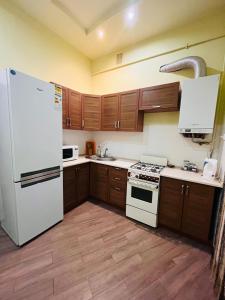 a kitchen with a white refrigerator and wooden cabinets at Iren Lviv apartment in Lviv