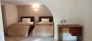Habitación con 2 camas, mesa y escritorio. en Tropic Garden Hotel, en Banjul