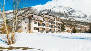 un bâtiment dans la neige devant une montagne dans l'établissement Hotel Verdeneve, à Opi