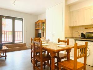 a kitchen with a wooden table and wooden chairs at Apartamentos Valle de Inclés MIKKA 3000 in Soldeu