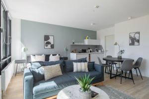 a living room with a blue couch and a table at Limehome Flensburg Holm in Flensburg