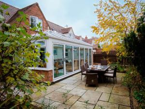 a conservatory with a table and chairs on a patio at Whippet Cottage in Evesham