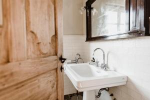 a bathroom with a sink and a mirror and a door at La Corte di Lu in Rocca D'Arazzo