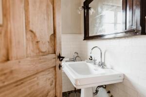 ein Badezimmer mit einem Waschbecken, einem Spiegel und einer Tür in der Unterkunft La Corte di Lu in Rocca D'Arazzo